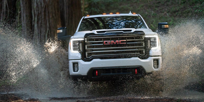 GMC Sierra splashing water while driving off-road trail